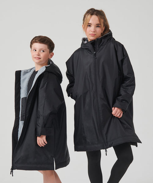 Two children wearing black raincoats on a light gray background
